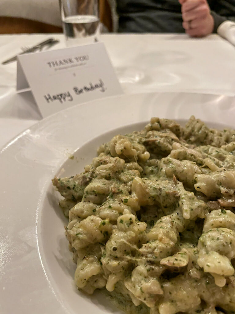 A close-up of Bistro Bella Vita’s Rotini Con Pollo in Grand Rapids, featuring rotini pasta, confit chicken, creamy pesto sauce, and parmesan cheese.